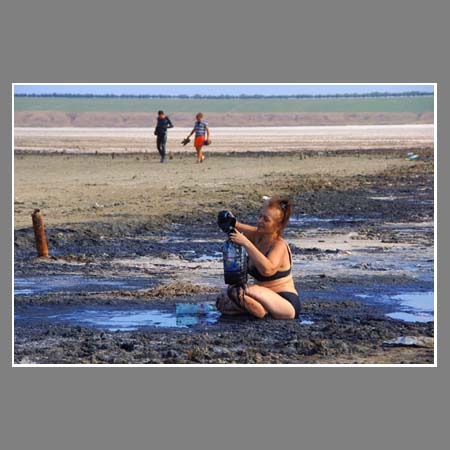 Женщина набирает лечебную грязь Соленого озера.